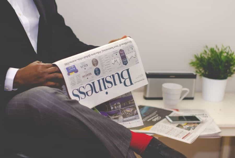 A man in a suit reads a business newspaper.