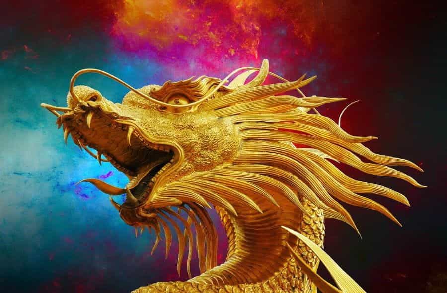 A golden statue of a roaring golden dragon in front of a colorful background.