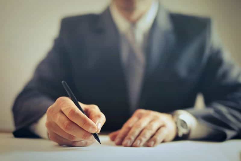 A businessman in a suit signs a deal.
