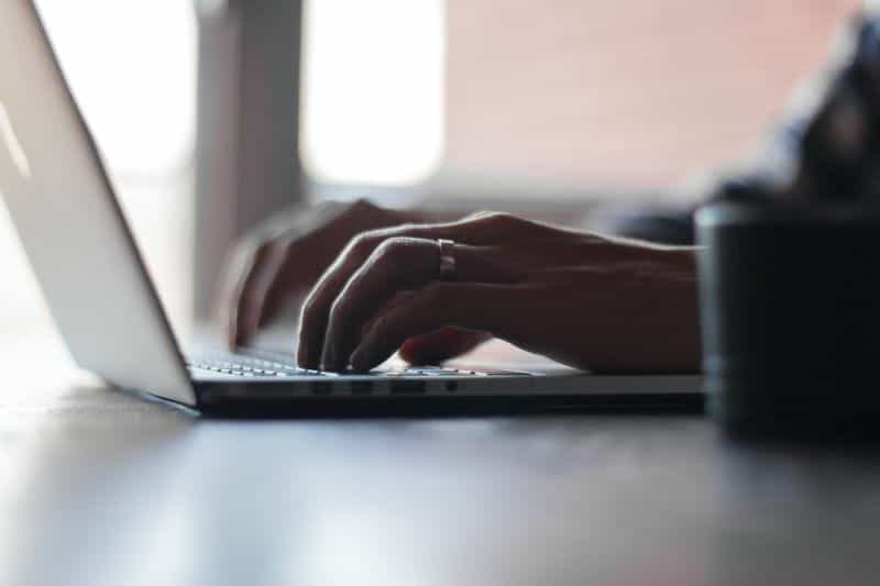 A person typing on the keyboard of a laptop.