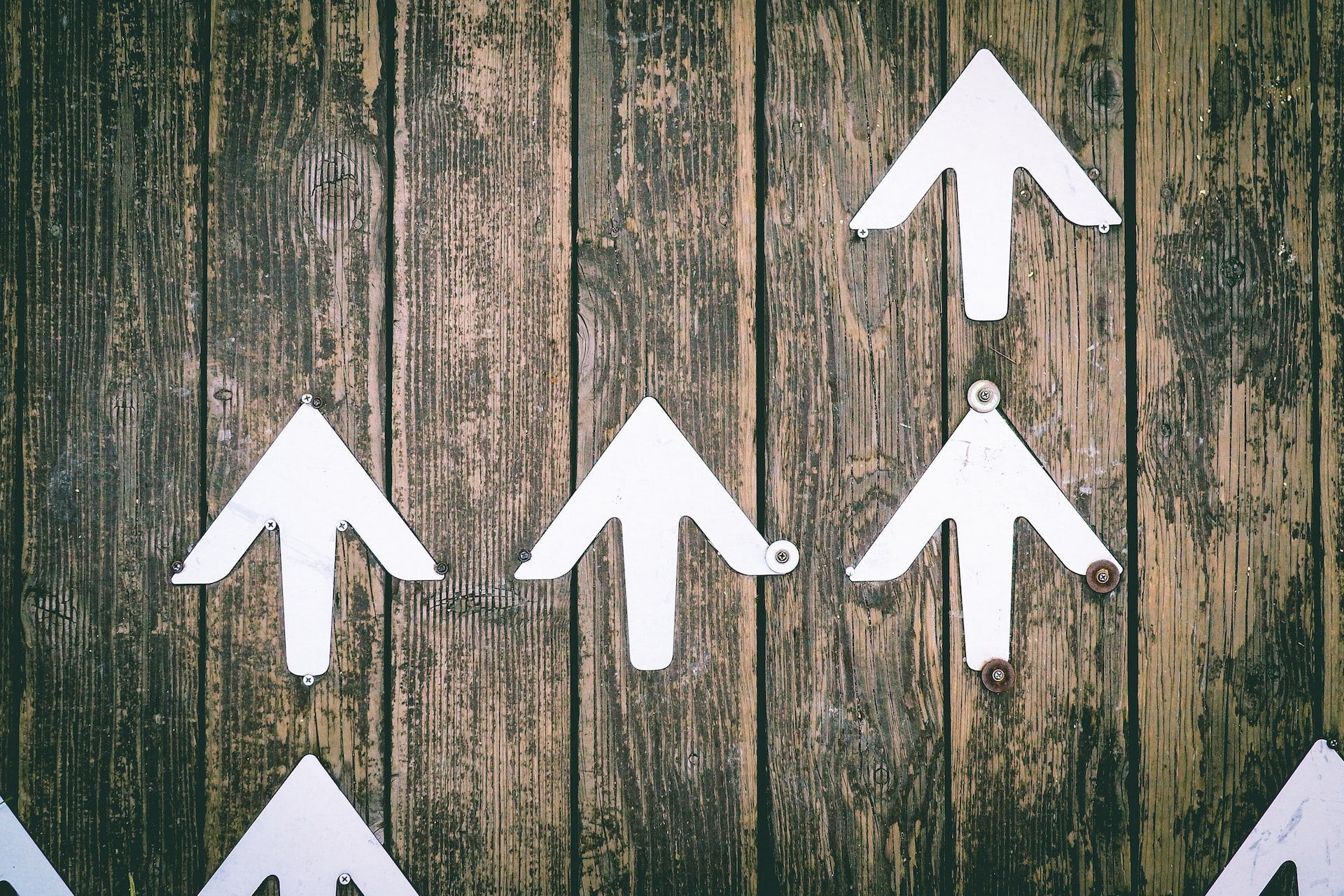 White arrows pointing up on a wooden surface.